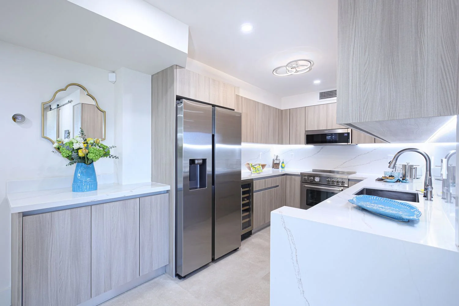Modern kitchen with gray cabinetry, white quartz counters, stainless steel appliances, and island