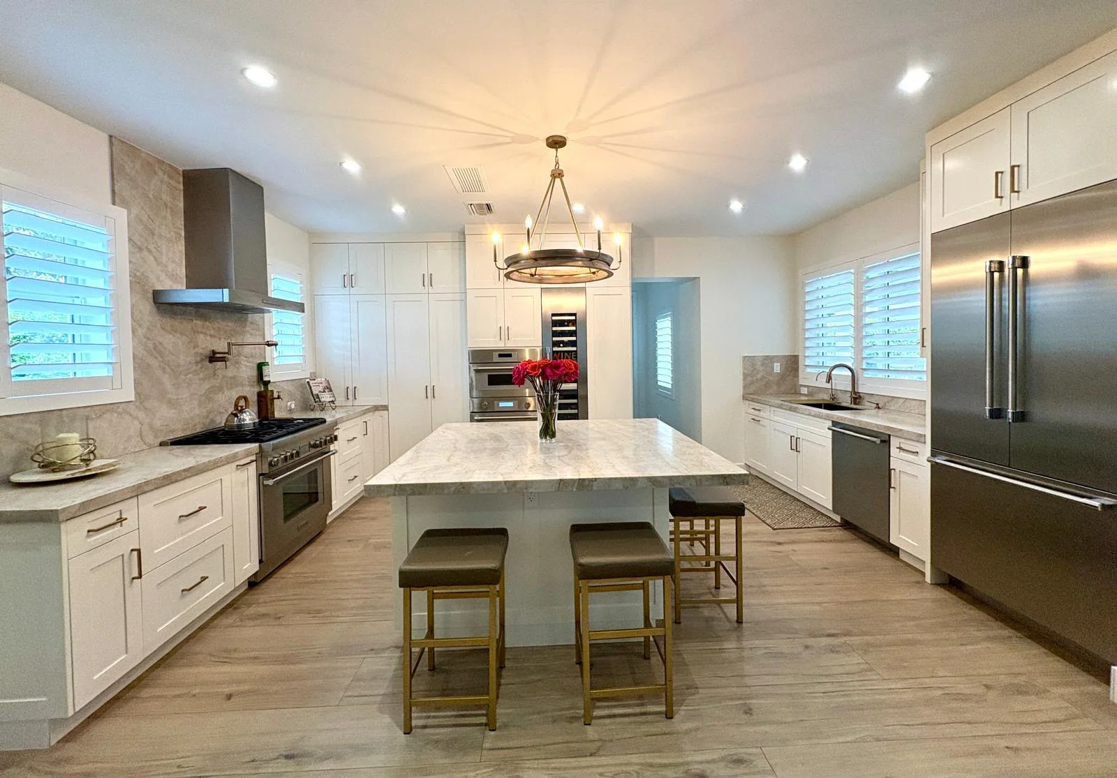 Modern kitchen with white cabinets, marble island, stainless steel appliances, and pendant lighting
