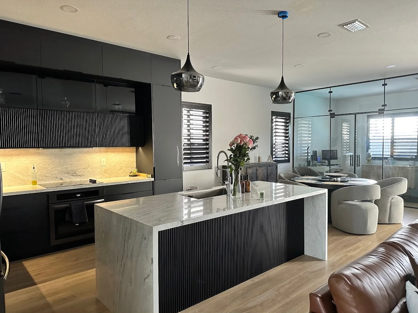 Modern kitchen with black cabinetry, marble island, and pendant lighting in Miami home