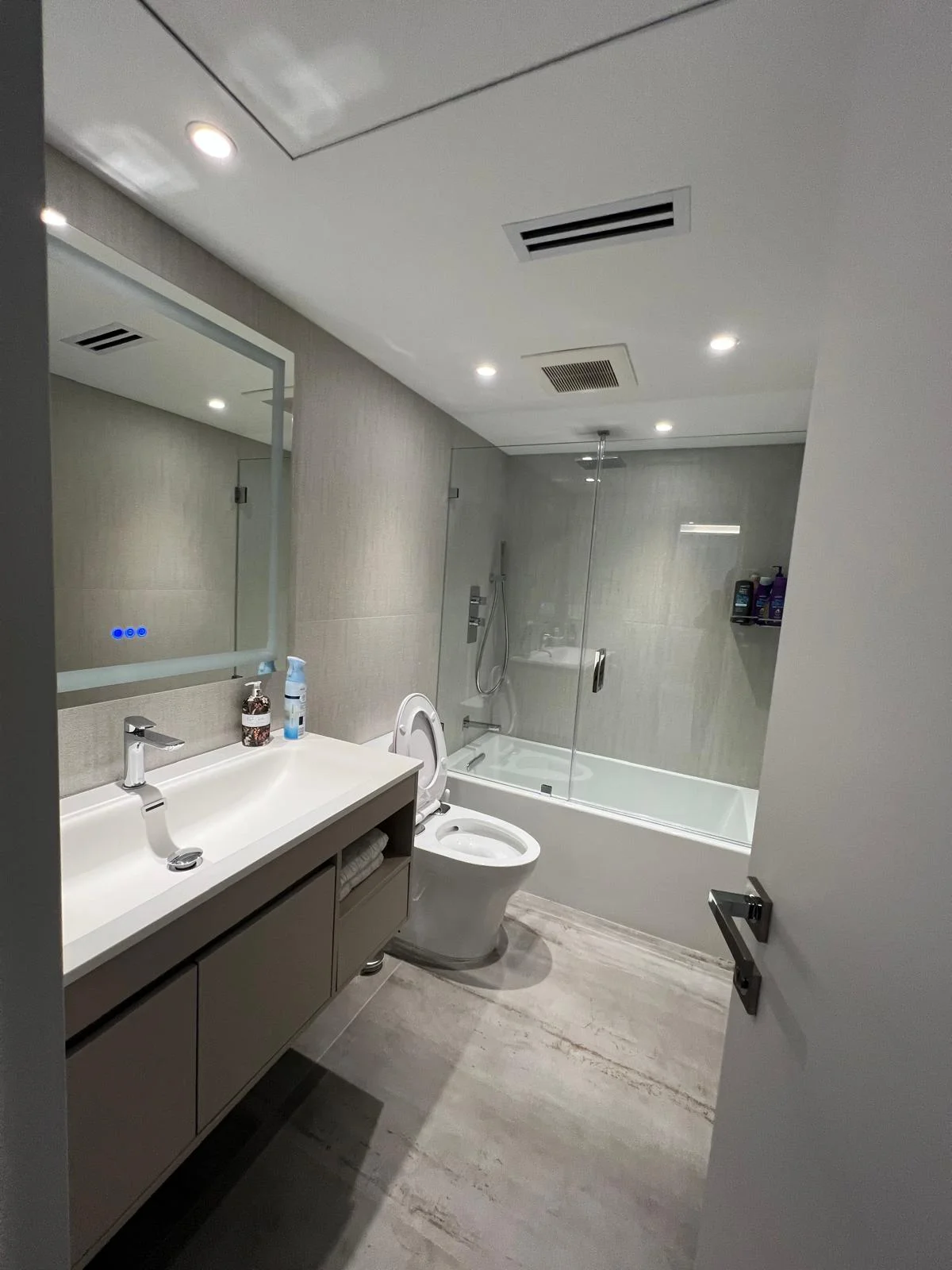 Modern bathroom with glass shower, floating vanity, and neutral tile flooring