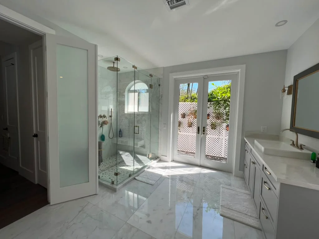 Modern master bathroom with glass shower enclosure, marble floors, and soaking tub